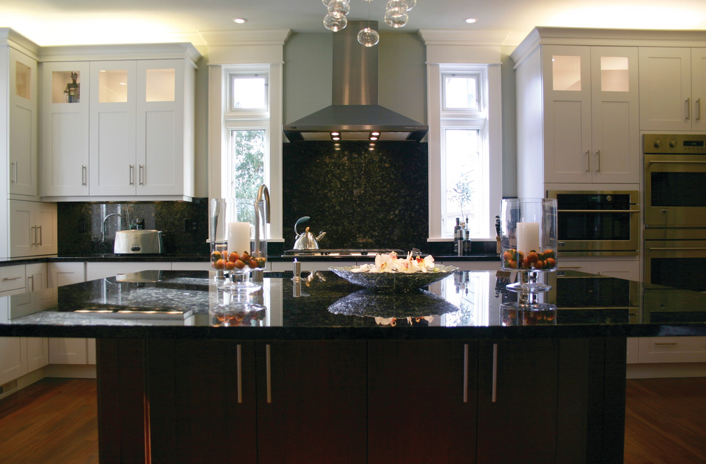 Exempel på ett mellanstort klassiskt kök, med en enkel diskho, skåp i shakerstil, vita skåp, marmorbänkskiva, svart stänkskydd, rostfria vitvaror, mellanmörkt trägolv, en köksö och stänkskydd i sten