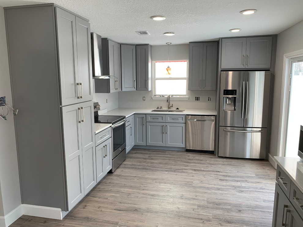 Mid-sized transitional l-shaped light wood floor and gray floor eat-in kitchen photo in Miami with an undermount sink, recessed-panel cabinets, blue cabinets, quartz countertops, white backsplash, stone slab backsplash, stainless steel appliances, no island and white countertops