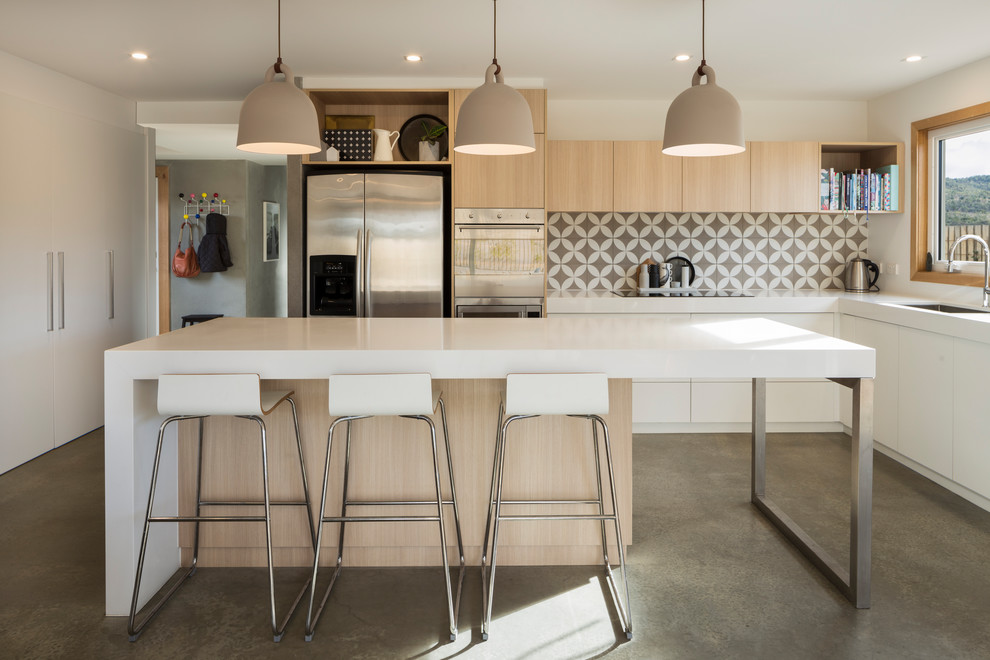 Moderne Küche in L-Form mit Unterbauwaschbecken, flächenbündigen Schrankfronten, hellen Holzschränken, Küchenrückwand in Beige, Küchengeräten aus Edelstahl, Kücheninsel und grauem Boden in Canberra - Queanbeyan