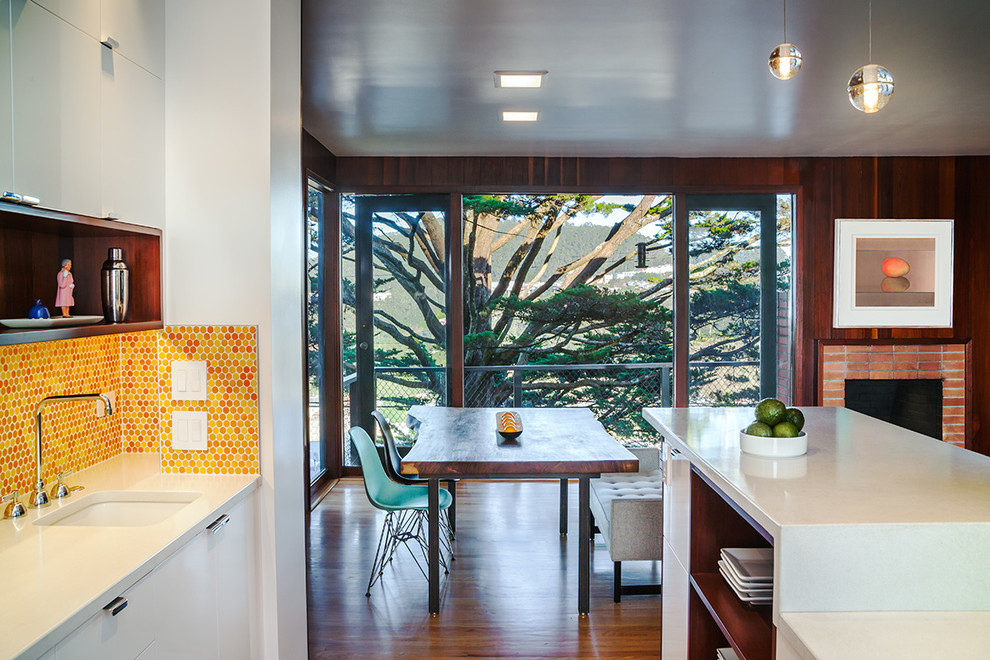 Bild på ett 60 tals kök och matrum, med en enkel diskho, orange stänkskydd och stänkskydd i mosaik