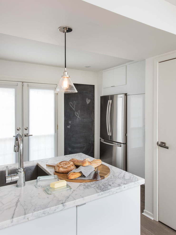 Foto på ett litet funkis kök, med en undermonterad diskho, släta luckor, vita skåp, marmorbänkskiva, vitt stänkskydd, stänkskydd i sten, rostfria vitvaror och mellanmörkt trägolv