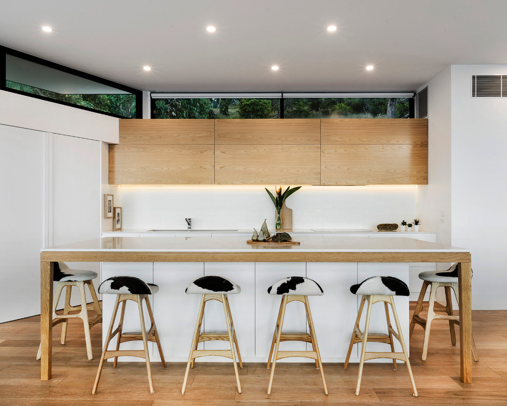Zweizeilige Moderne Küche mit flächenbündigen Schrankfronten, braunem Holzboden, Kücheninsel und hellen Holzschränken in Melbourne