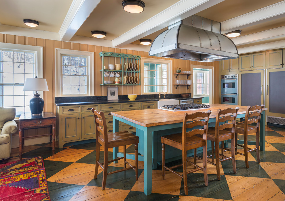 Farmhouse painted wood floor open concept kitchen photo in Burlington with a farmhouse sink, beaded inset cabinets, green cabinets and soapstone countertops