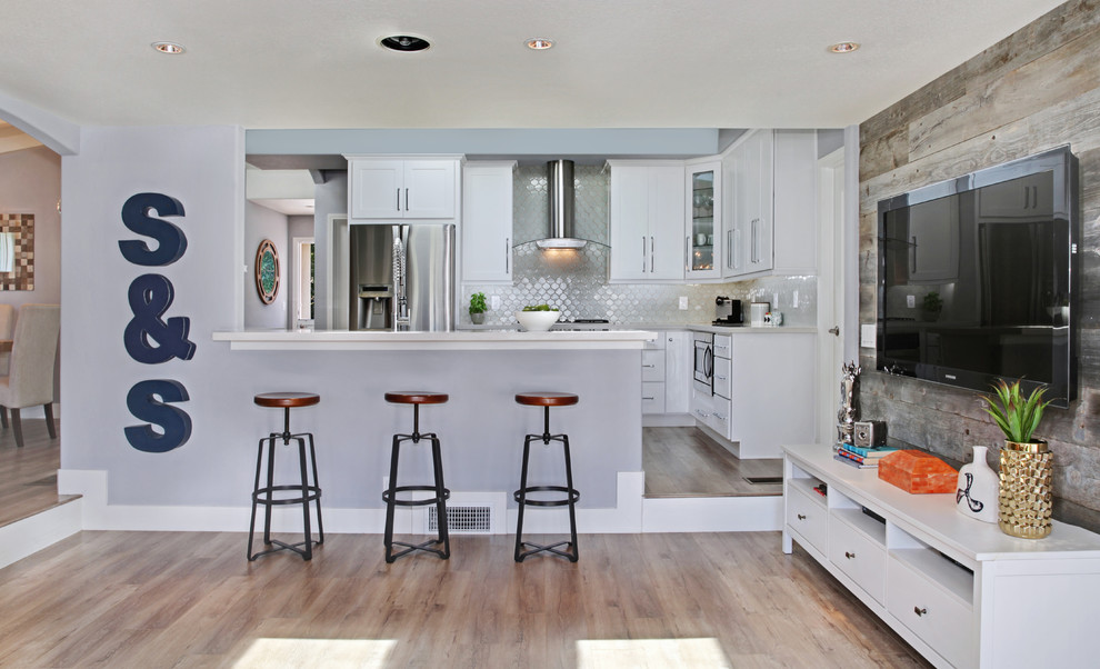 Inspiration for a medium sized contemporary galley kitchen/diner in Orange County with a belfast sink, shaker cabinets, white cabinets, engineered stone countertops, multi-coloured splashback, mosaic tiled splashback, stainless steel appliances, light hardwood flooring and a breakfast bar.