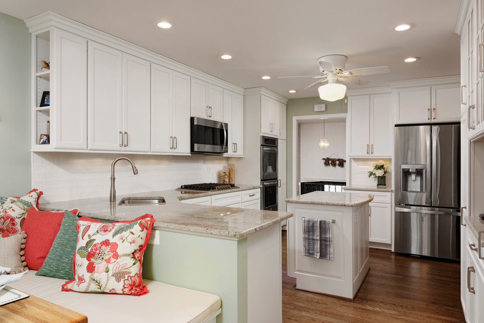 Large traditional l-shaped kitchen in DC Metro with a submerged sink, flat-panel cabinets, white cabinets, granite worktops, white splashback, ceramic splashback, stainless steel appliances, medium hardwood flooring and an island.
