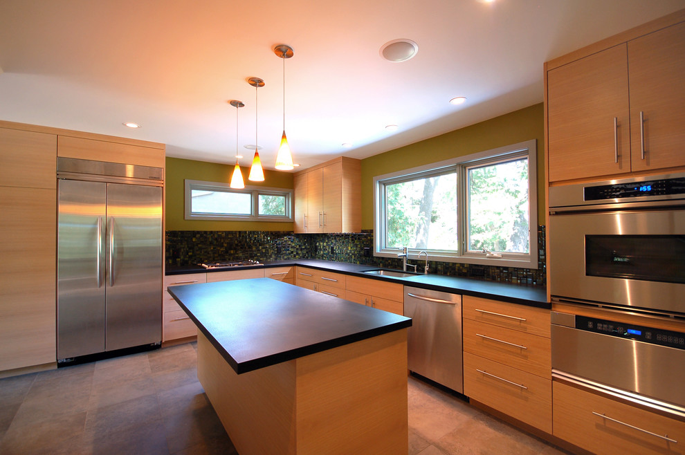 Example of a minimalist l-shaped slate floor enclosed kitchen design in Minneapolis with an undermount sink, flat-panel cabinets, light wood cabinets, green backsplash, mosaic tile backsplash, stainless steel appliances and an island
