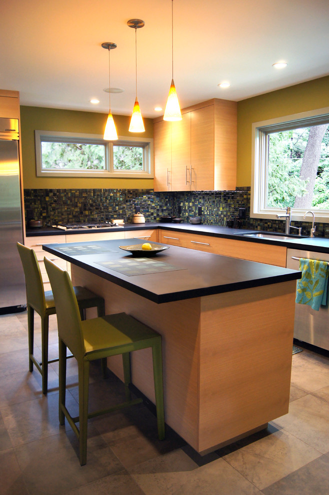 Свежая идея для дизайна: угловая, отдельная кухня в стиле модернизм с врезной мойкой, плоскими фасадами, светлыми деревянными фасадами, зеленым фартуком и техникой из нержавеющей стали - отличное фото интерьера