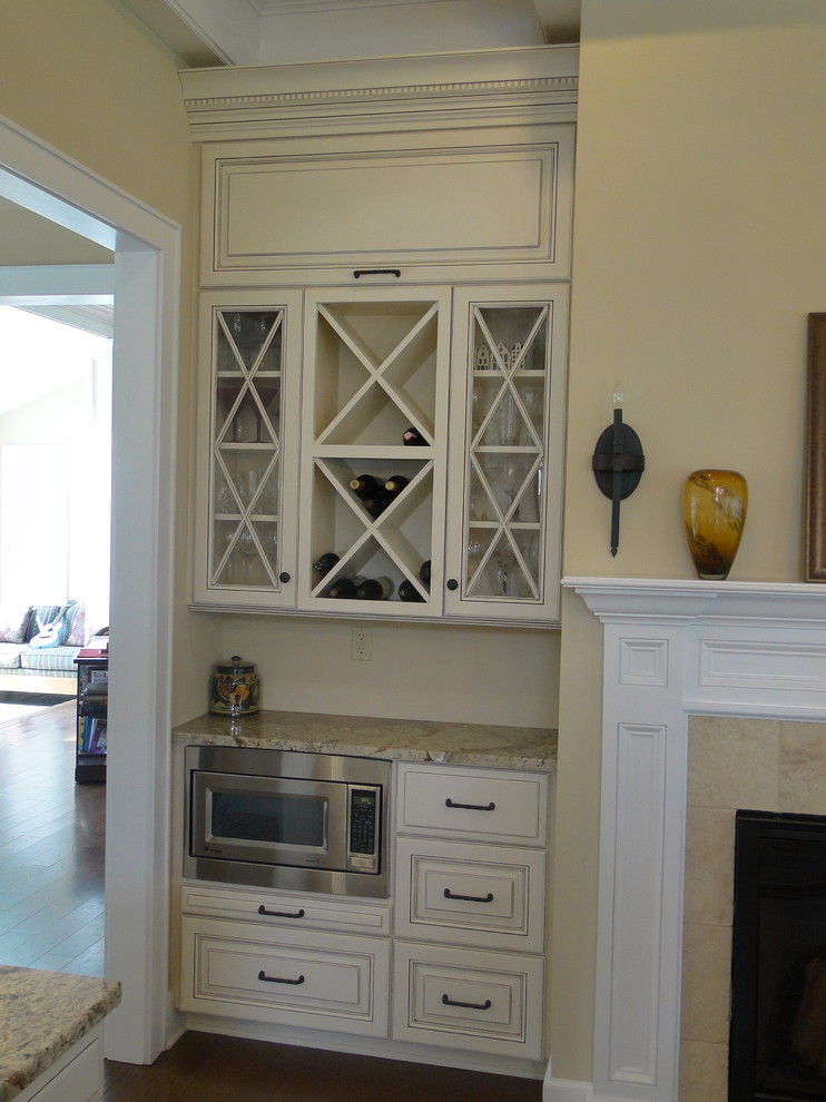 Inredning av ett klassiskt stort kök, med en undermonterad diskho, luckor med upphöjd panel, vita skåp, granitbänkskiva, rostfria vitvaror, ljust trägolv och en köksö