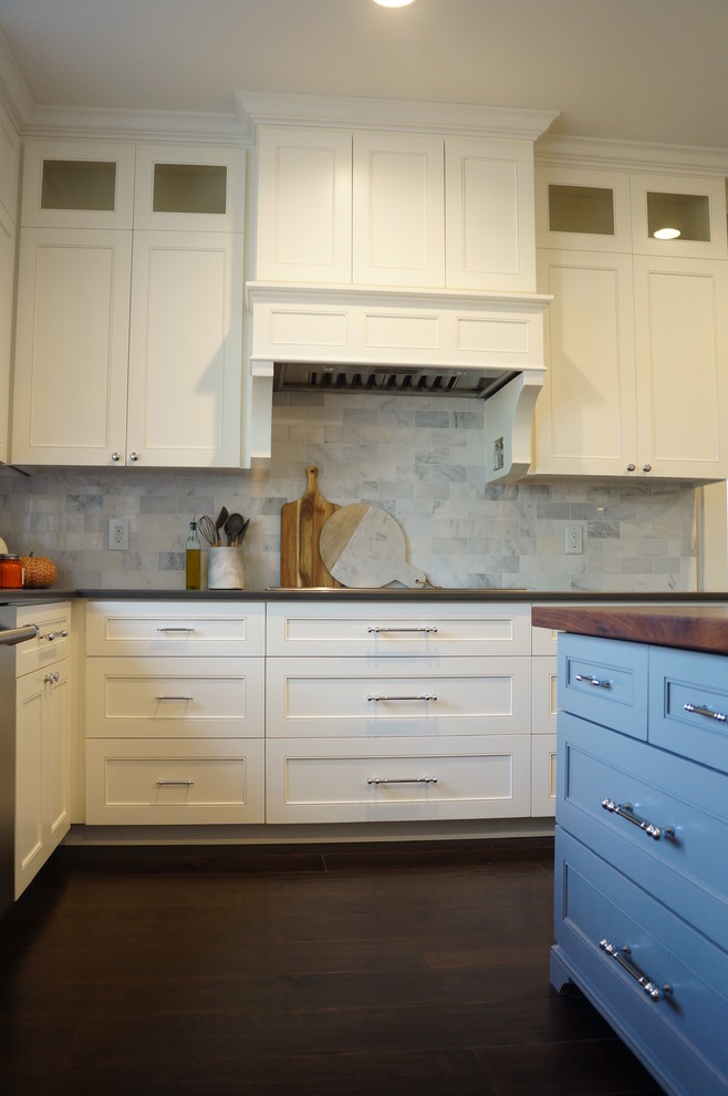 This is an example of an expansive traditional u-shaped enclosed kitchen in Boston with a belfast sink, recessed-panel cabinets, grey cabinets, engineered stone countertops, grey splashback, porcelain splashback, stainless steel appliances, dark hardwood flooring, multiple islands, black floors and white worktops.