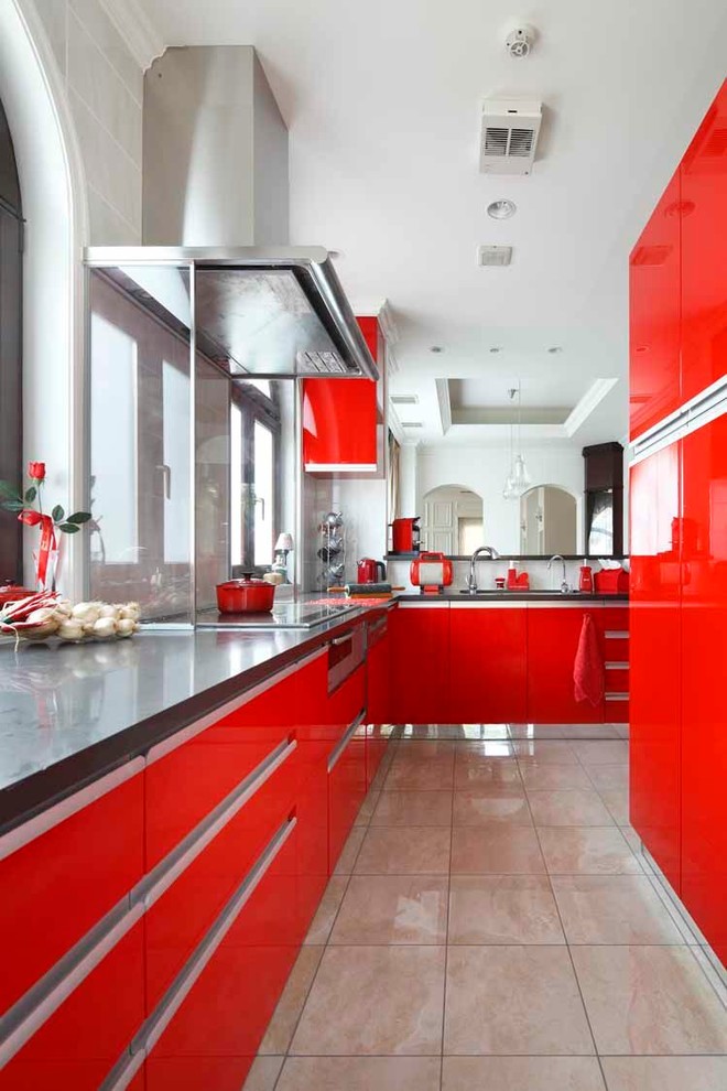 Bild på ett funkis l-kök, med släta luckor, röda skåp, glaspanel som stänkskydd och marmorgolv