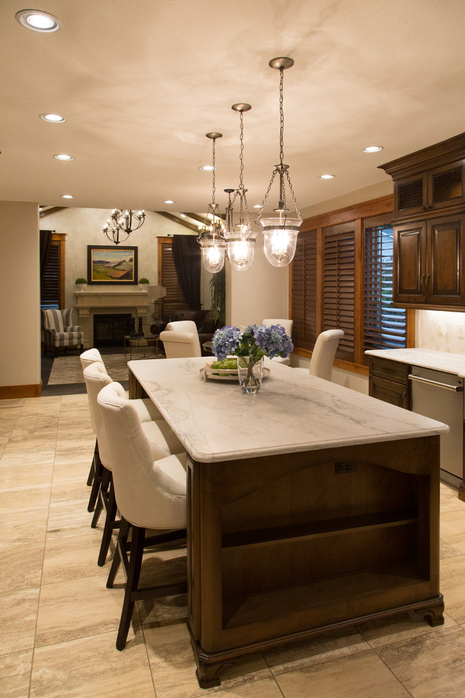Inspiration for a large timeless u-shaped travertine floor enclosed kitchen remodel in Portland with a farmhouse sink, raised-panel cabinets, dark wood cabinets, granite countertops, beige backsplash, stone tile backsplash, stainless steel appliances and an island