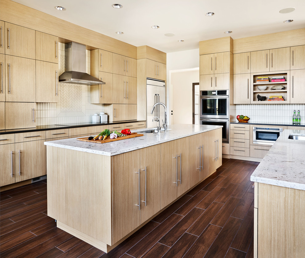 Large contemporary l-shaped open plan kitchen in Portland with flat-panel cabinets, light wood cabinets, engineered stone countertops, grey splashback, ceramic splashback, stainless steel appliances, porcelain flooring, multiple islands and brown floors.