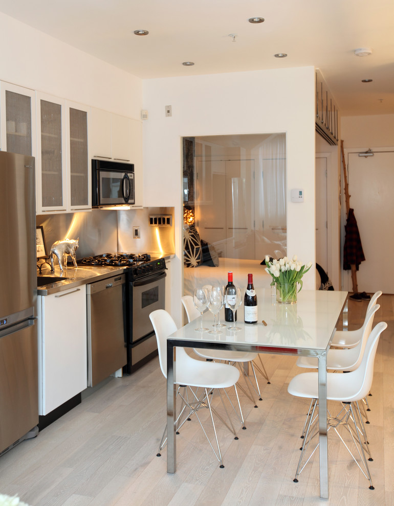 Contemporary kitchen/diner in Vancouver with glass-front cabinets, stainless steel worktops, metallic splashback, metal splashback and stainless steel appliances.