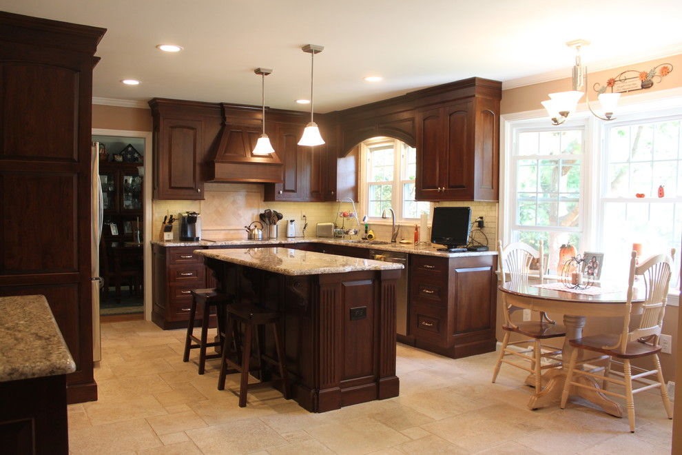 Example of a mid-sized classic l-shaped travertine floor enclosed kitchen design in Philadelphia with an undermount sink, raised-panel cabinets, dark wood cabinets, granite countertops, beige backsplash, stone tile backsplash, stainless steel appliances and an island