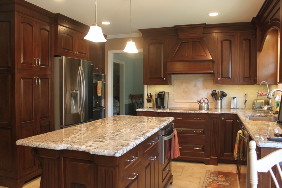 Example of a mid-sized classic l-shaped travertine floor enclosed kitchen design in Philadelphia with an undermount sink, raised-panel cabinets, dark wood cabinets, granite countertops, beige backsplash, stone tile backsplash, stainless steel appliances and an island