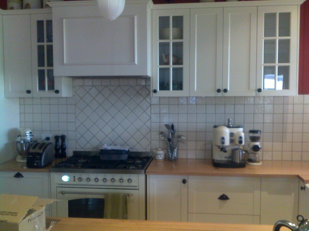 Bild på ett mellanstort lantligt kök, med en dubbel diskho, luckor med infälld panel, vita skåp, träbänkskiva, vitt stänkskydd, stänkskydd i keramik, färgglada vitvaror, mellanmörkt trägolv och en köksö