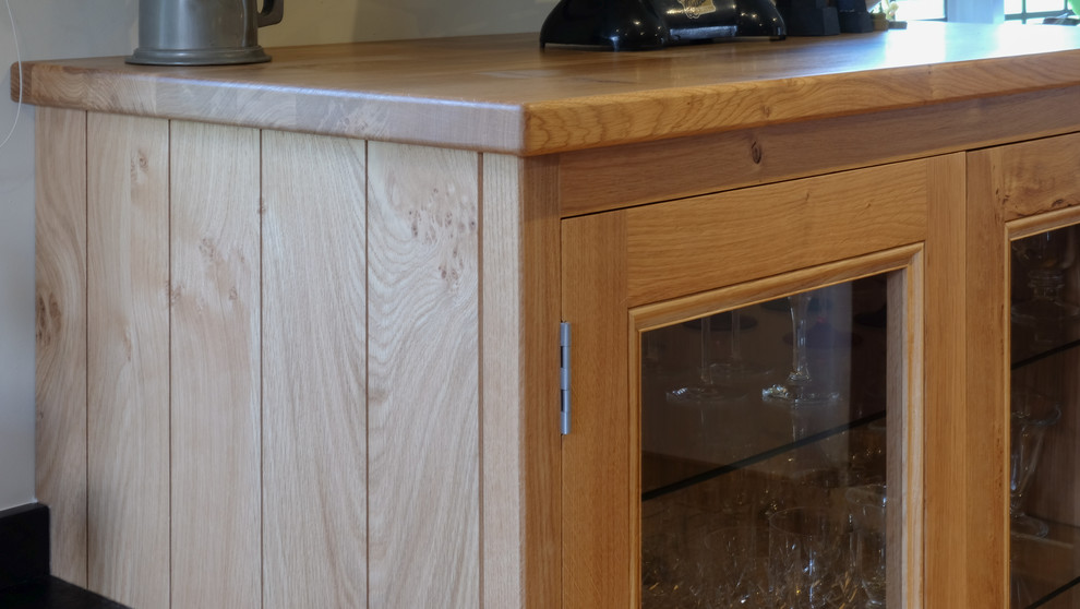 Design ideas for a small traditional single-wall open plan kitchen in Hampshire with recessed-panel cabinets, light wood cabinets, granite worktops, black splashback, stone slab splashback, medium hardwood flooring and black worktops.