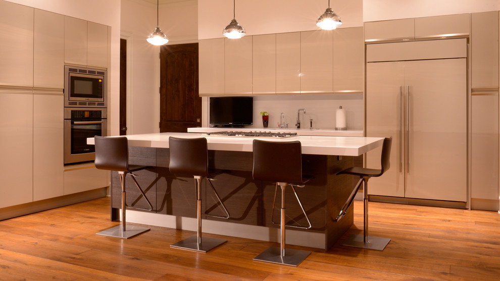 Esempio di una grande cucina moderna con lavello da incasso, ante lisce, ante bianche, top in granito, elettrodomestici in acciaio inossidabile e pavimento in legno massello medio