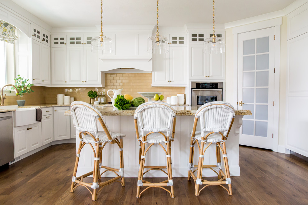 Kitchen - large coastal u-shaped medium tone wood floor and brown floor kitchen idea in Other with a farmhouse sink, raised-panel cabinets, stainless steel appliances, an island, white cabinets, orange backsplash, subway tile backsplash and beige countertops