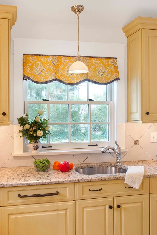 Mid-sized elegant porcelain tile eat-in kitchen photo in Philadelphia with an undermount sink, raised-panel cabinets, yellow cabinets, granite countertops, beige backsplash, porcelain backsplash, paneled appliances and an island