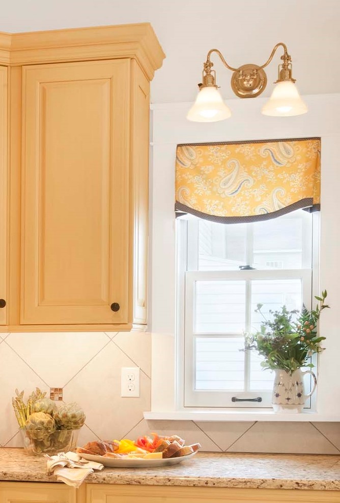 Mid-sized elegant porcelain tile and beige floor eat-in kitchen photo in Philadelphia with an undermount sink, raised-panel cabinets, yellow cabinets, granite countertops, beige backsplash, porcelain backsplash, paneled appliances and an island