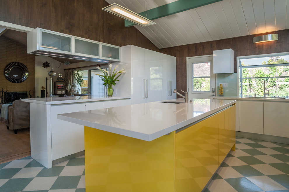 Inspiration for a mid-sized contemporary galley linoleum floor eat-in kitchen remodel in San Francisco with flat-panel cabinets, white cabinets, stainless steel appliances, an island, a drop-in sink, solid surface countertops, gray backsplash and stone slab backsplash