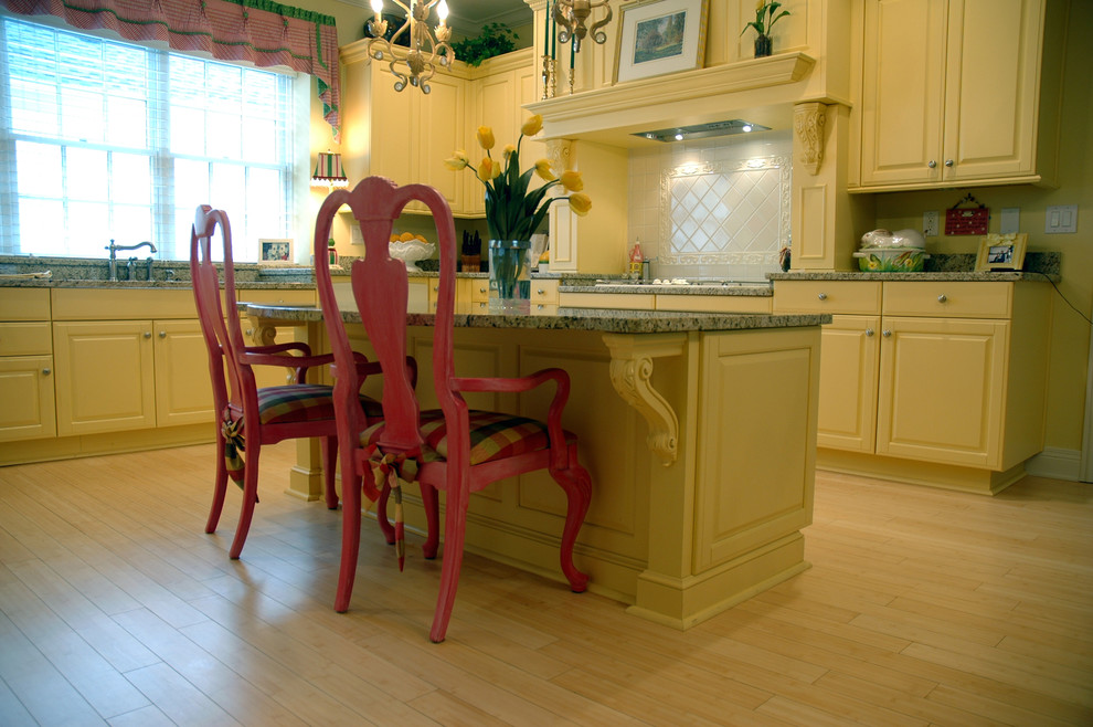 Elegant u-shaped light wood floor eat-in kitchen photo in Indianapolis with an undermount sink, raised-panel cabinets, yellow cabinets, granite countertops, white appliances and an island