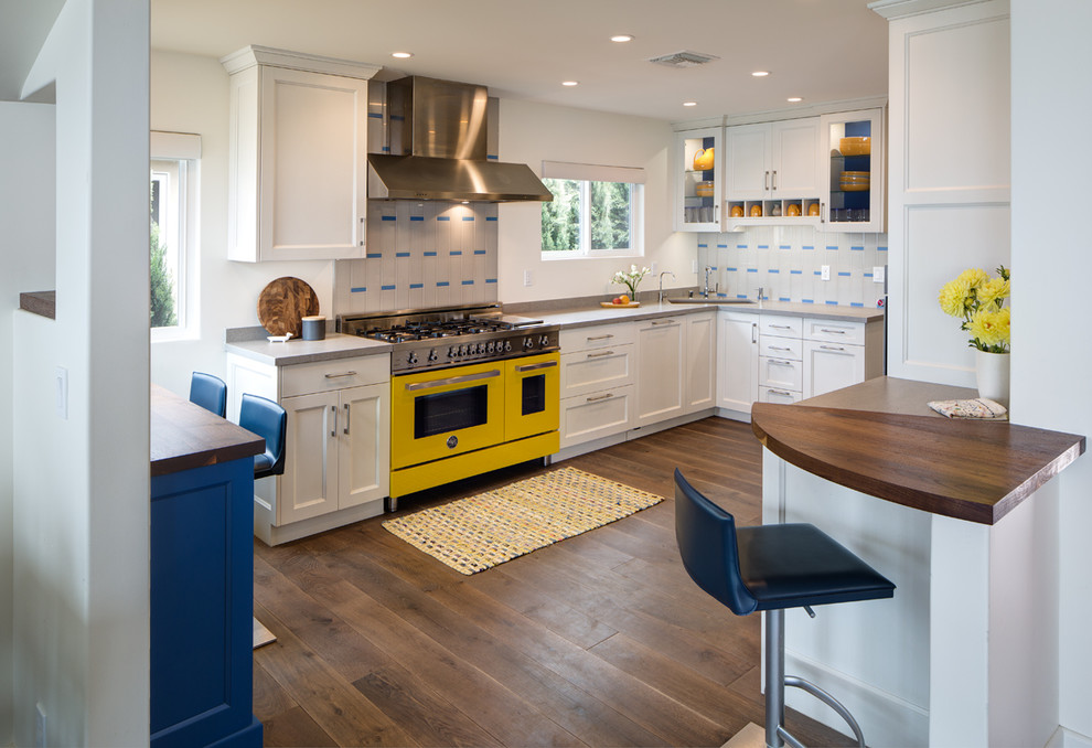 Inspiration for a large coastal u-shaped laminate floor eat-in kitchen remodel in San Diego with an undermount sink, white cabinets, ceramic backsplash, colored appliances, shaker cabinets, wood countertops, gray backsplash and no island