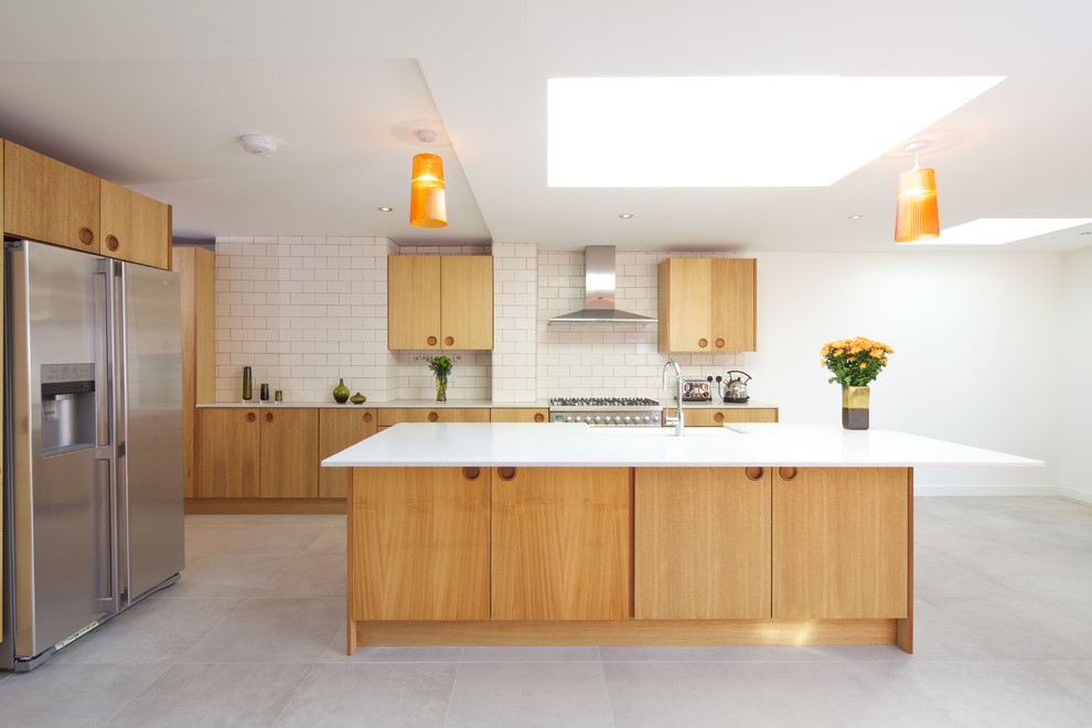 Moderne Küche in L-Form mit flächenbündigen Schrankfronten, hellen Holzschränken, Küchenrückwand in Weiß, Rückwand aus Metrofliesen, Küchengeräten aus Edelstahl, Schieferboden und Kücheninsel in London