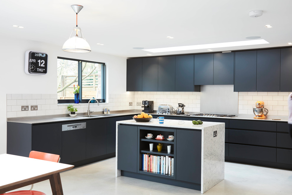 Photo of a large contemporary l-shaped open plan kitchen in London with a double-bowl sink, flat-panel cabinets, blue cabinets, stainless steel worktops, white splashback, metro tiled splashback, integrated appliances, an island and grey floors.