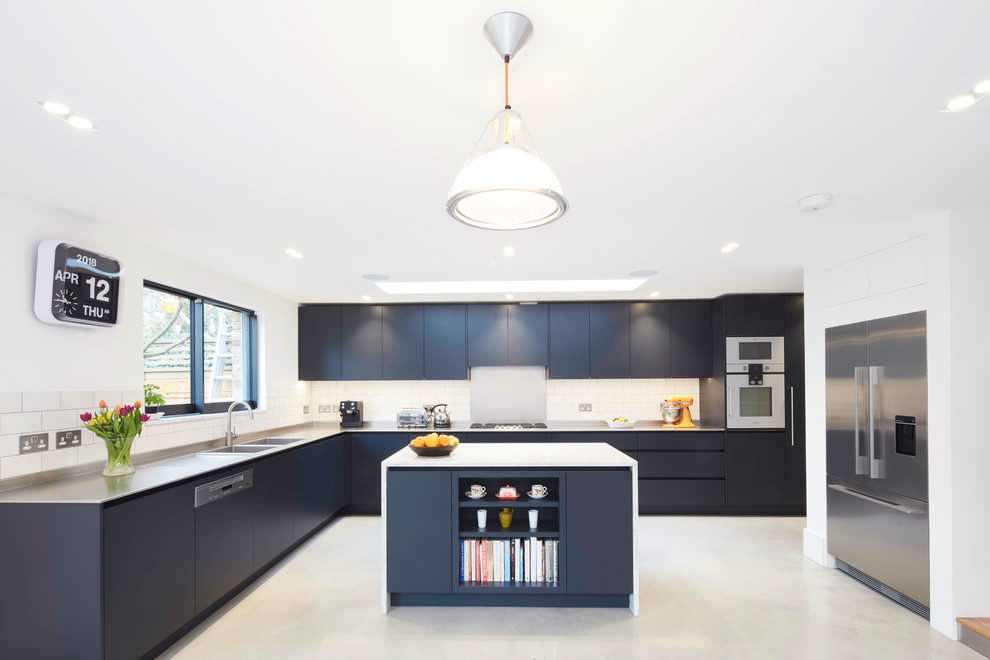 Foto på ett stort funkis kök, med en dubbel diskho, släta luckor, blå skåp, bänkskiva i rostfritt stål, vitt stänkskydd, stänkskydd i tunnelbanekakel, integrerade vitvaror, en köksö och grått golv