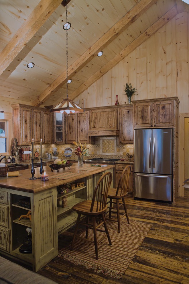Inspiration for a rustic kitchen in New Orleans with a belfast sink, distressed cabinets, wood worktops, beige splashback, stainless steel appliances, dark hardwood flooring, an island, brown floors, beige worktops and raised-panel cabinets.