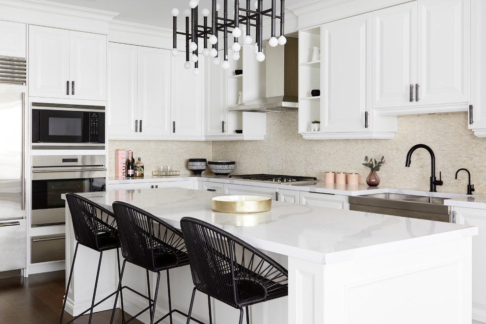Inspiration for a contemporary l-shaped kitchen in Toronto with a belfast sink, raised-panel cabinets, white cabinets, beige splashback, mosaic tiled splashback, stainless steel appliances, dark hardwood flooring, an island, brown floors and white worktops.