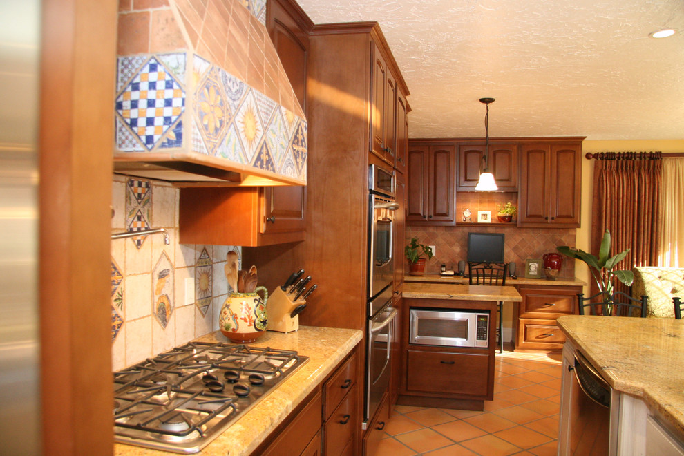 Cette image montre une cuisine américaine méditerranéenne en bois brun de taille moyenne avec un évier encastré, un plan de travail en granite, un électroménager en acier inoxydable, tomettes au sol et îlot.