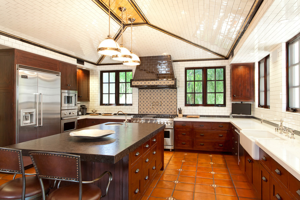 ロサンゼルスにあるおしゃれなキッチン (エプロンフロントシンク、濃色木目調キャビネット、シルバーの調理設備、テラコッタタイルの床) の写真