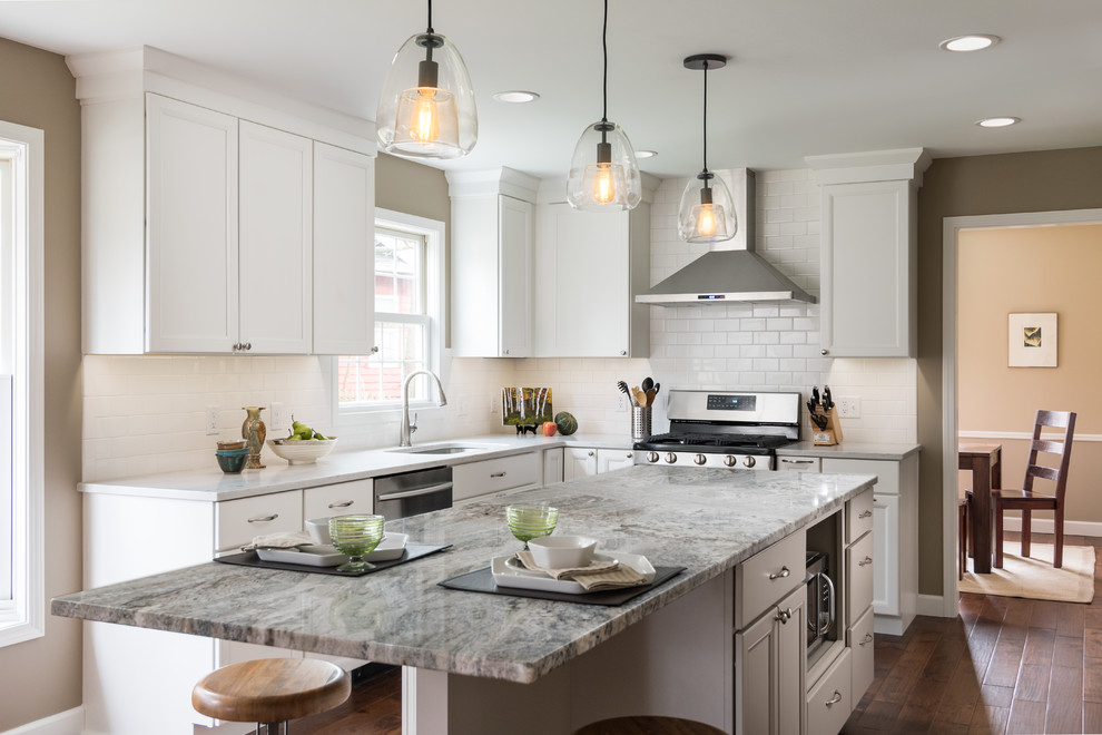 Inspiration for a classic l-shaped kitchen in Grand Rapids with a submerged sink, shaker cabinets, white cabinets, white splashback, metro tiled splashback, stainless steel appliances, dark hardwood flooring, an island and brown floors.