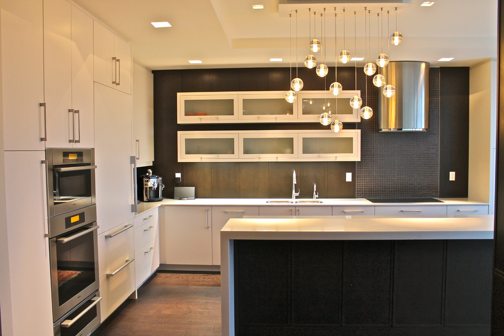Design ideas for a contemporary l-shaped kitchen in Toronto with flat-panel cabinets, white cabinets, black splashback and integrated appliances.