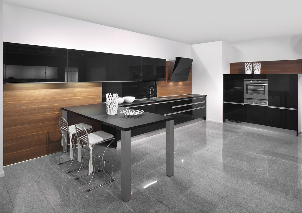 Moderne Küche mit Küchengeräten aus Edelstahl, flächenbündigen Schrankfronten, schwarzen Schränken, Küchenrückwand in Schwarz und Glasrückwand in Sonstige