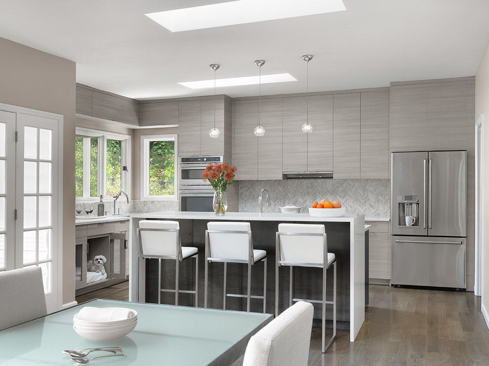 Example of a mid-sized trendy l-shaped medium tone wood floor and brown floor eat-in kitchen design in St Louis with flat-panel cabinets, gray cabinets, gray backsplash, stainless steel appliances, an island, white countertops, quartz countertops and porcelain backsplash