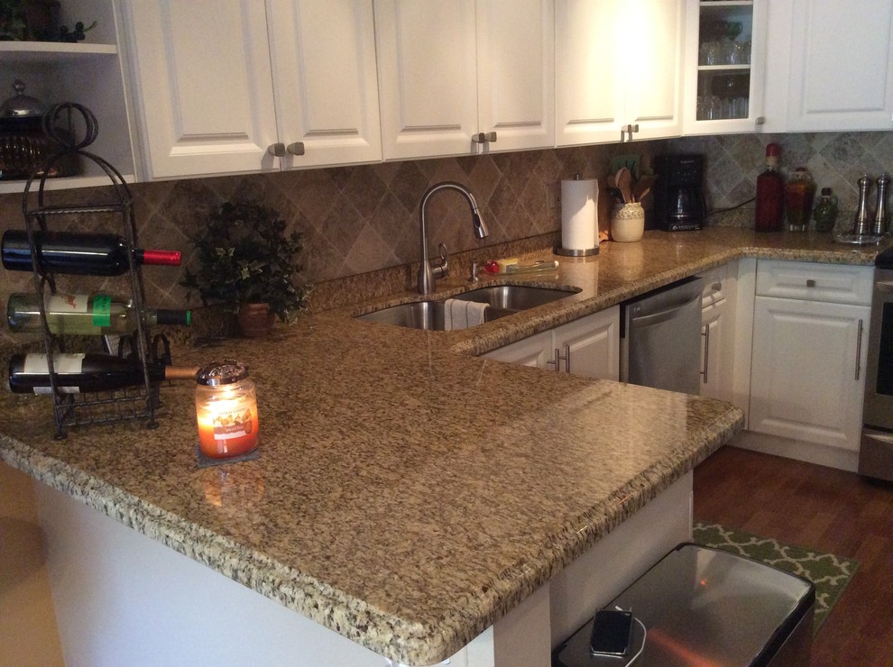 Klassisk inredning av ett mellanstort kök, med en undermonterad diskho, luckor med upphöjd panel, vita skåp, granitbänkskiva, beige stänkskydd, stänkskydd i stenkakel, rostfria vitvaror, mellanmörkt trägolv och en köksö