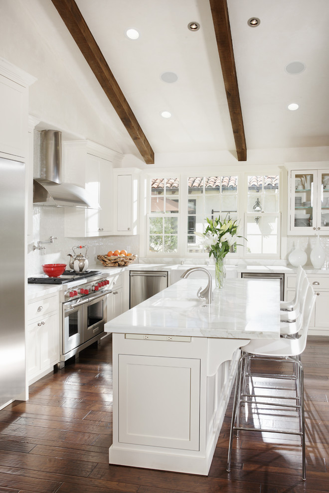 Photo of a mediterranean l-shaped kitchen in San Francisco with shaker cabinets, white cabinets, white splashback and stainless steel appliances.