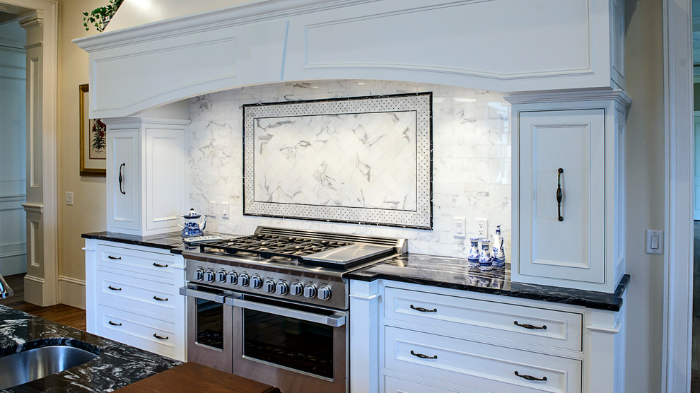 Klassische Küche mit Granit-Arbeitsplatte, Küchenrückwand in Schwarz, Rückwand aus Metrofliesen, Küchengeräten aus Edelstahl, braunem Holzboden und Kücheninsel in Atlanta