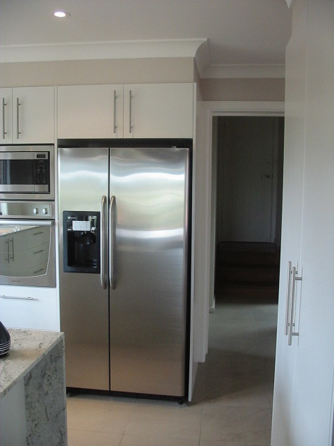 Foto de cocina moderna grande con fregadero bajoencimera, puertas de armario blancas, encimera de granito, suelo de baldosas de terracota y una isla