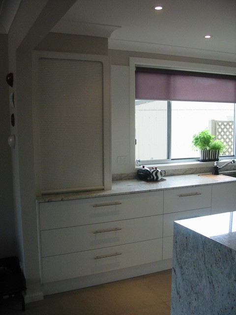 Foto på ett stort funkis kök, med en undermonterad diskho, vita skåp, granitbänkskiva, klinkergolv i terrakotta och en köksö
