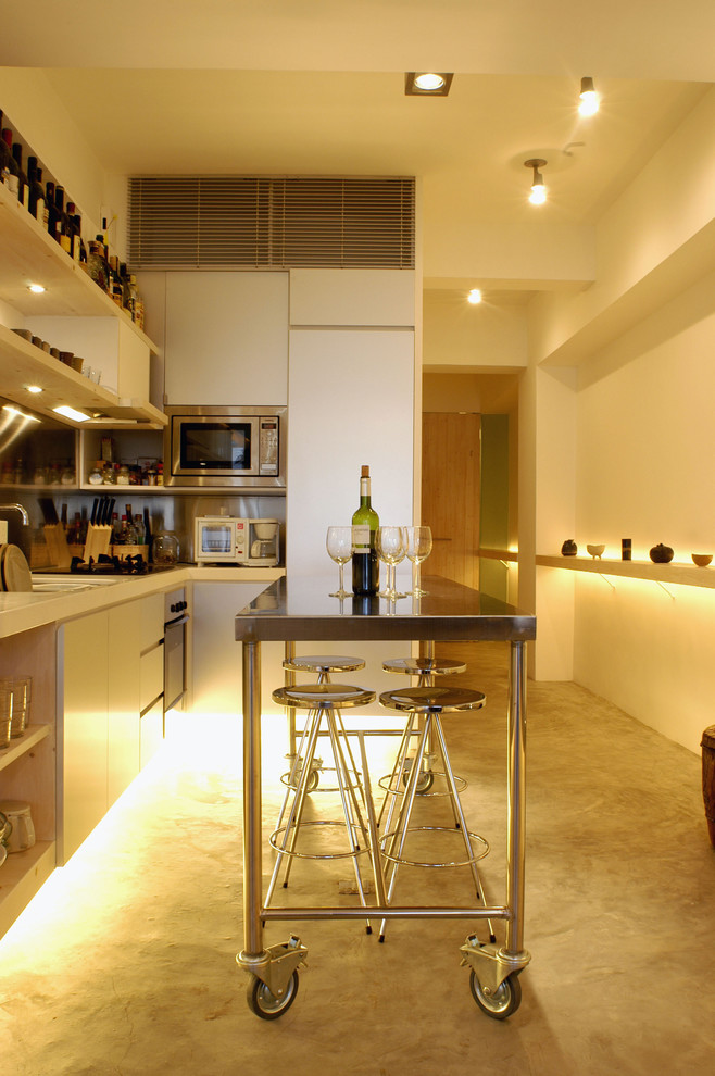 Modern inredning av ett kök, med släta luckor, vita skåp, bänkskiva i rostfritt stål och rostfria vitvaror