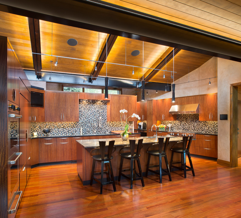 Photo of a contemporary u-shaped kitchen in Denver with a submerged sink, flat-panel cabinets, medium wood cabinets, multi-coloured splashback, mosaic tiled splashback, integrated appliances, medium hardwood flooring, an island and brown floors.