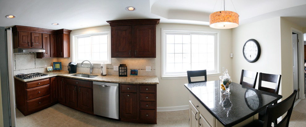 Photo of a classic kitchen/diner in Detroit with dark wood cabinets, beige splashback and stainless steel appliances.