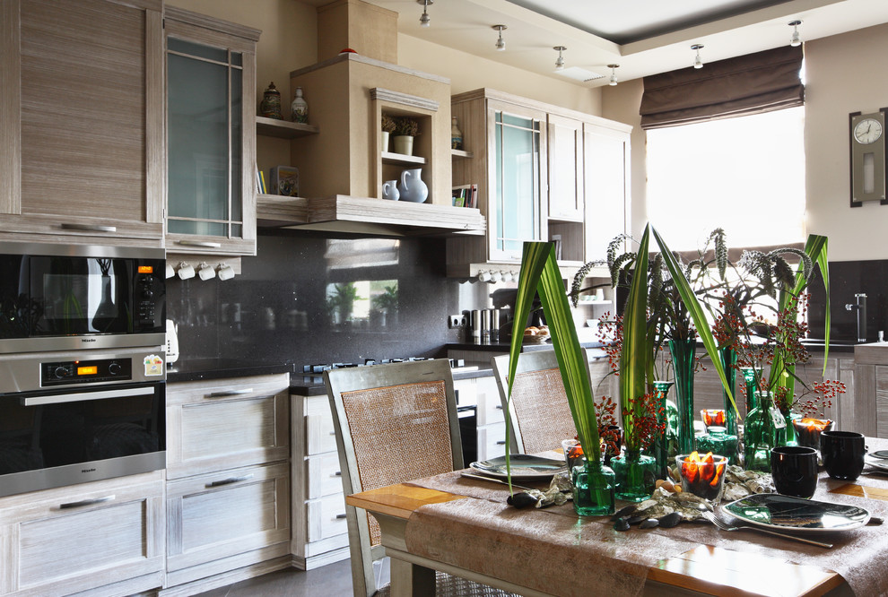 Modern inredning av ett kök och matrum, med luckor med infälld panel, skåp i slitet trä, svart stänkskydd och rostfria vitvaror