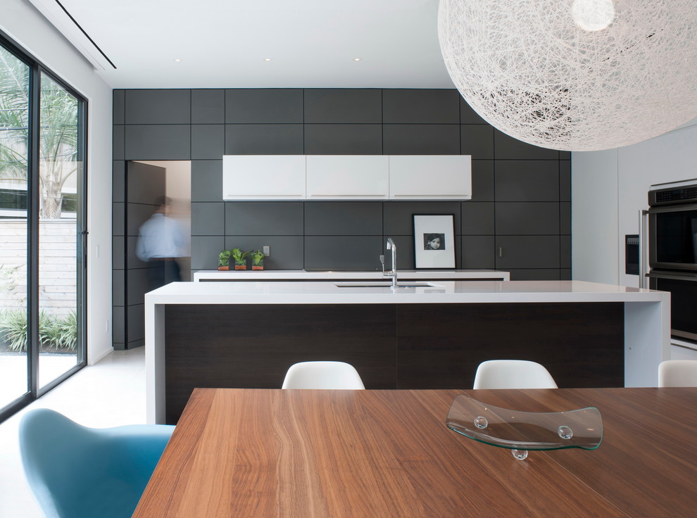 Идея дизайна: параллельная, серо-белая кухня в стиле модернизм с обеденным столом, плоскими фасадами, белыми фасадами и островом
