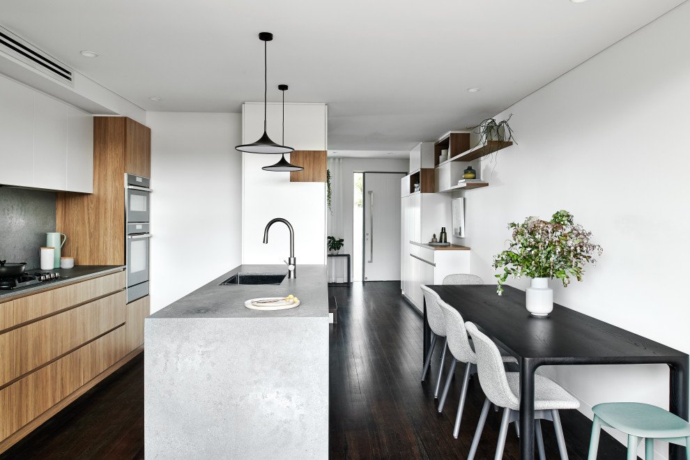 Exempel på ett mellanstort modernt grå grått kök, med en undermonterad diskho, släta luckor, skåp i mellenmörkt trä, bänkskiva i glas, grått stänkskydd, stänkskydd i sten, svarta vitvaror, mörkt trägolv, en halv köksö och svart golv